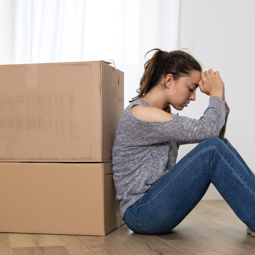 woman praying while sitting on the floor with boxes