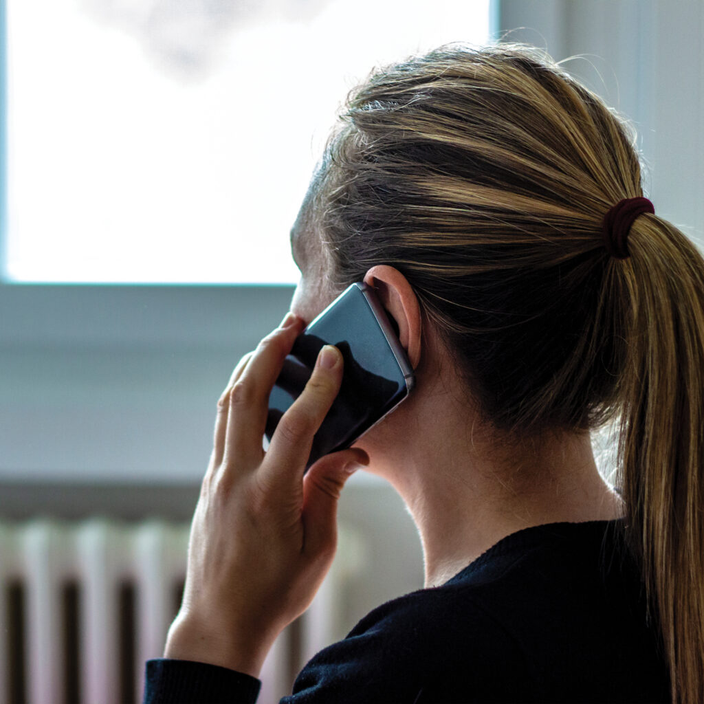 A lady talking on the phone while looking out the window.